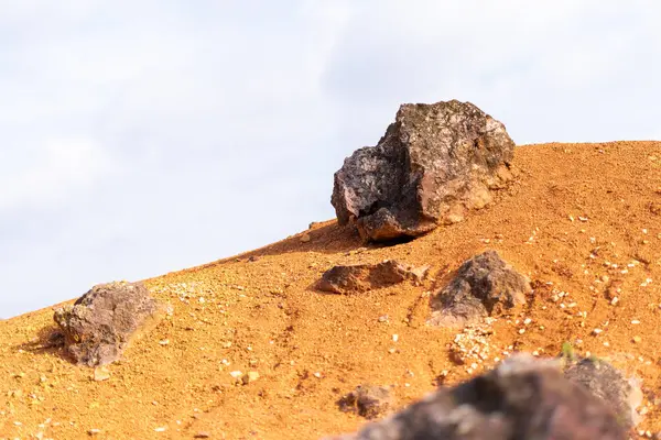 Terk edilmiş bir boksit madeninde parlak turuncu renklerle erozyona uğramış bir kayalık oluşumu.