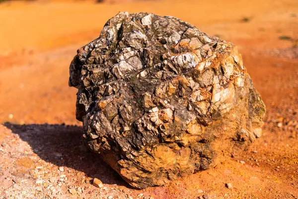 Terk edilmiş bir boksit madeninde parlak turuncu renklerle erozyona uğramış bir kayalık oluşumu.