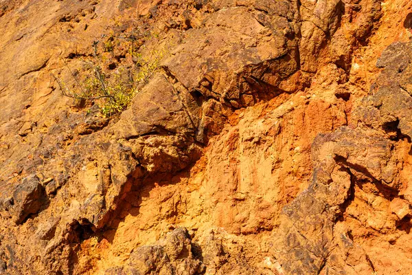 Terk edilmiş bir boksit madeninde parlak turuncu renklerle erozyona uğramış bir kayalık oluşumu.