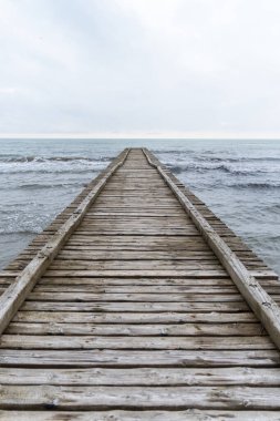 Adriyatik Denizi 'ne çıkan tahta iskele İtalya' da bulutlu bir sonbahar plajında.