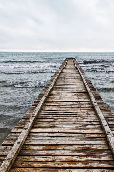 Adriyatik Denizi 'ne çıkan tahta iskele İtalya' da bulutlu bir sonbahar plajında.