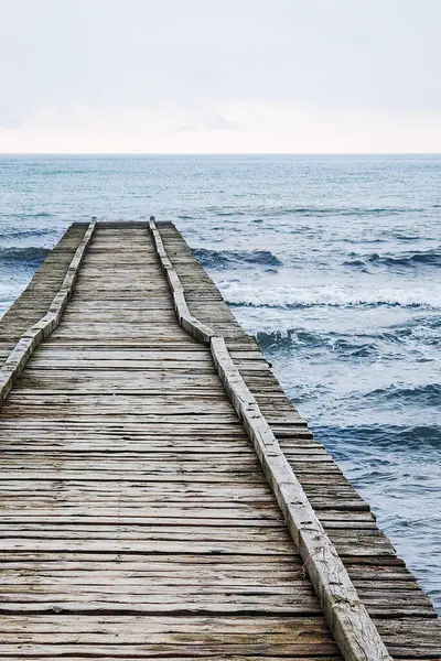 Adriyatik Denizi 'ne çıkan tahta iskele İtalya' da bulutlu bir sonbahar plajında.