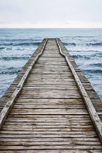 Adriyatik Denizi 'ne çıkan tahta iskele İtalya' da bulutlu bir sonbahar plajında.