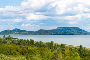 Arkasında volkanik dağlar ve bulutlar olan yaz Balaton manzarası