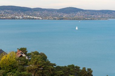 Sonbahar güneşinde Balaton Gölü 'nde bir yelkenli gemi. Arka planda Balatonfued var.