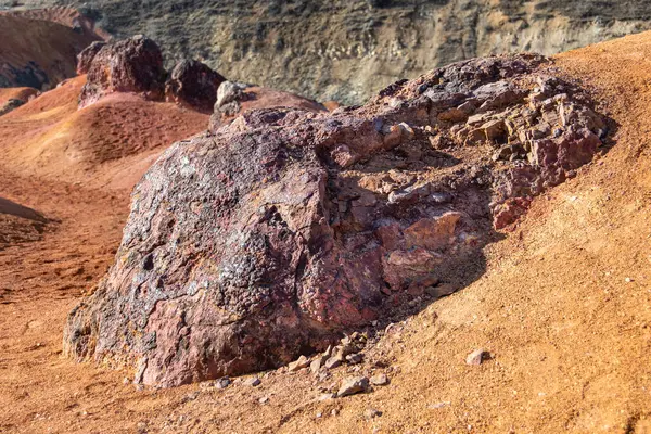 Terk edilmiş bir boksit madeninde parlak turuncu renklerle erozyona uğramış bir kayalık oluşumu.