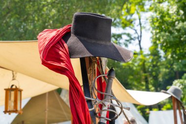 Askeri bir kampta siyah bir keçeli şapka ve bir ortaçağ kılıcı kabzası.