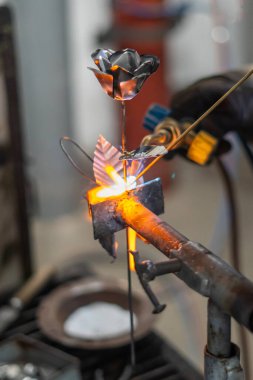 Metal bir gülü kaynak yapan bir zanaatkar.