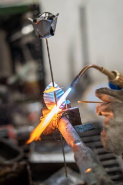 Metal bir gülü kaynak yapan bir zanaatkar.