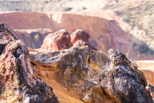 Terk edilmiş bir boksit madeninde parlak turuncu renklerle erozyona uğramış bir kayalık oluşumu.