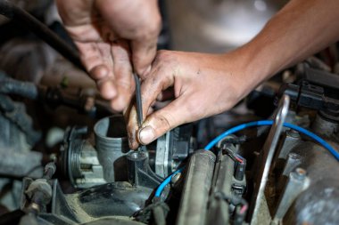 Araba tamircisi eski bir arabanın motorunda çalışıyor.