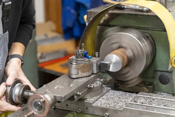 Atölyede eski bir torna makinesi üzerinde çalışan bir işçi.