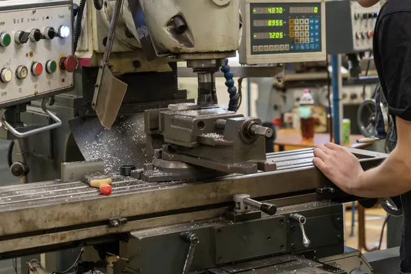 Atölyede değirmen makinesinde çalışan bir adam.