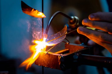 Metal bir gülü kaynak yapan bir zanaatkar.