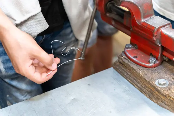 Kırmızı bir mengenenin yanında bir kalbi telden bükmek.
