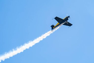 Mavi gökyüzünde uçan dumanlı küçük bir uçak