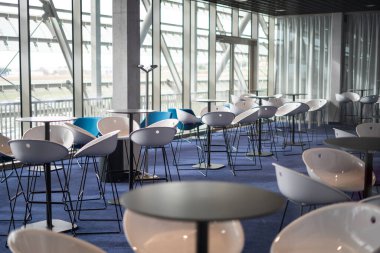 Camdan duvarları olan ultra modern bir salonda modern sandalyeler ve koltuklar.