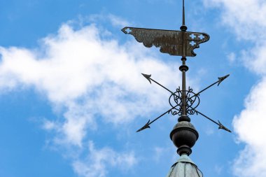 Bulutlu mavi gökyüzünün önünde pusula ile rüzgar gülü