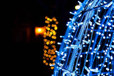 Gece caddesinde büyük mavi ışıklı Noel balosu süslemeleri.