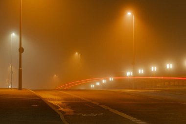 Eve aceleyle gitmek - Sisteki bir köprüde gecenin karanlığında arabanın stop lambasından hafif izler.