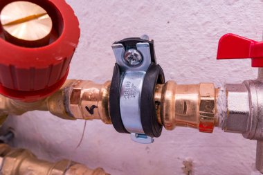 Duvara klemple tutturulmuş vanaları olan bir boruya yakın çekim