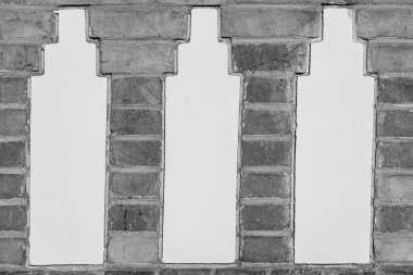 Üç beyaz alçı panelli kırmızı tuğla bir duvar. Ortasında el boyaması 