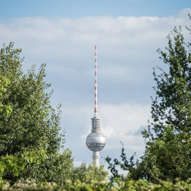 Berlin TV Kulesi (Fernsehturm) bir yaz günü yemyeşil ağaçlar tarafından çerçevelenmiştir..