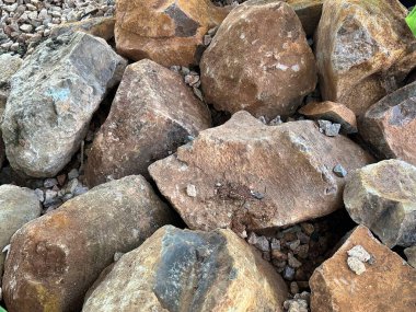 Geniş bir doğal kaya yığınının farklı boyutlarda, şekillerde ve toprak tonlarında detaylı bir görüntüsü. Doku ve aşınmış yüzeyler doğal aşınma ve katman etkilerini gösteriyor..