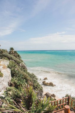Tropikal bitkiler, Tulum, Quintana Roo, Meksika 'da kıyıya vuran dalgalarla beyaz kumlu sahile doğru bir uçurum izler..