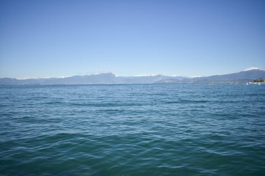 Peschiera del Garda 'daki sahile, İtalya' daki Garda Gölü 'ne, sakin sulara, arka planda dağlara