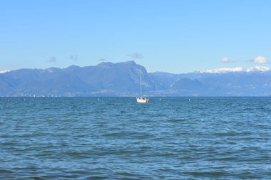 İtalya, Peschiera del Garda 'daki Garda Gölü' nde huzurlu bir manzara. Gölün sakin suları, yatlar ve karlı uzak dağlar.. 