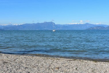 Peschiera del Garda 'daki sahile, İtalya' daki Garda Gölü 'ne, sakin sulara, arka planda dağlara