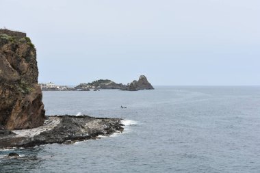 Bulutlu bir günde Aci Trezza yakınlarındaki denizdeki Kiklops (Faraglioni dei Ciclopi) kayalıkları, Aci Castello, Sicilya, İtalya manzaralı. 