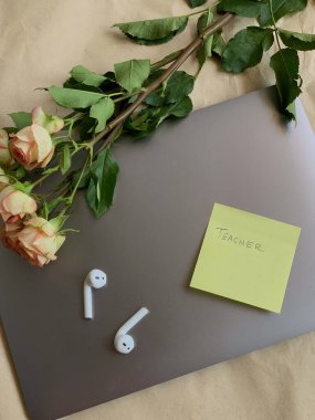 İş yeri. Çevrimiçi eğitim kavramı. E-öğrenme. Online eğitim. Laptop, kulaklıklar, çiçekler, üst manzara, fotokopi alanı. Modern çalışma ortamı. El yazısı öğretmenli yapışkan bir not..