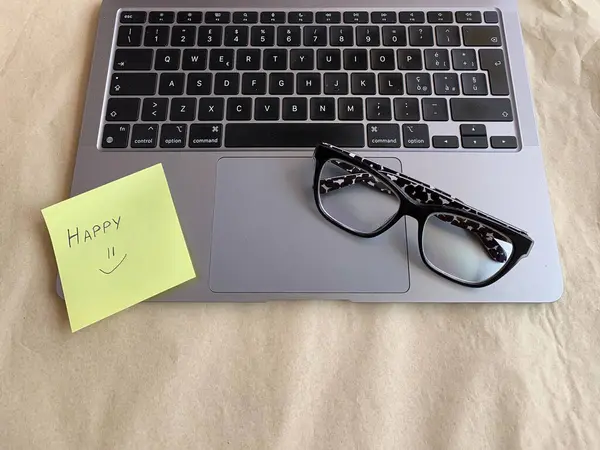 İş yeri. Çevrimiçi eğitim kavramı. E-öğrenme. Online eğitim. Dizüstü bilgisayar ve gözlük, üst görüş, kopyalama alanı, afiş. Modern çalışma ortamı. El yazısıyla yazılmış mutlu bir not.. 