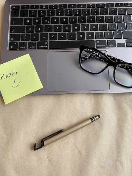 İş yeri. Çevrimiçi eğitim kavramı. E-öğrenme. Online eğitim. Dizüstü bilgisayar, kalem ve gözlük, üst görüş, fotokopi alanı, afiş. Modern çalışma ortamı. El yazısıyla yazılmış mutlu bir not.. 