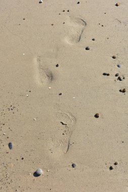 İnce kumsalda çıplak ayak izleri var. Dalgaların yumuşadığı sahilde. İnsan ayağının izleri. Seyahat ve tatil kavramı. Sicilya, İtalya 'da Cefalu yakınlarında bir plaj. İtalya 'ya git. Rahatla..