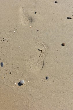 İnce kumsalda çıplak ayak izleri var. Dalgaların yumuşadığı sahilde. İnsan ayağının izleri. Seyahat ve tatil kavramı. Sicilya, İtalya 'da Cefalu yakınlarında bir plaj. İtalya 'ya git. Rahatla..