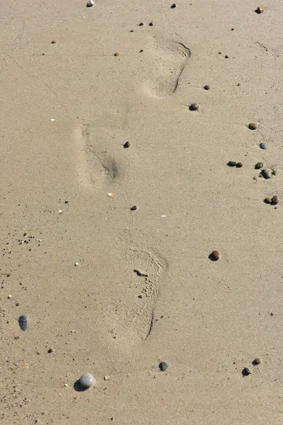 İnce kumsalda çıplak ayak izleri var. Dalgaların yumuşadığı sahilde. İnsan ayağının izleri. Seyahat ve tatil kavramı. Sicilya, İtalya 'da Cefalu yakınlarında bir plaj. İtalya 'ya git. Rahatla..