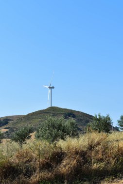 İtalya, Sicilya 'daki dağda rüzgar türbini. Rüzgar türbini ve kırsal İtalyan yaz manzarası. Mountain Eolic Parkı. Yenilenebilir enerji kavramı, yeşil ekolojik enerji üretimi. 