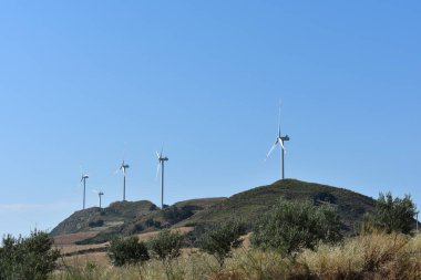 İtalya, Sicilya 'daki dağlarda rüzgar türbinleri. Rüzgar türbinleri ve kırsal İtalyan yaz manzarası. Mountain Eolic Parkı. Yenilenebilir enerji kavramı, yeşil ekolojik enerji üretimi. 