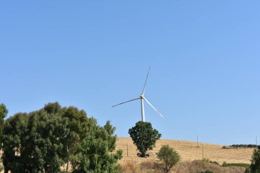 İtalya, Sicilya 'daki dağda rüzgar türbini. Rüzgar türbini ve kırsal İtalyan yaz manzarası. Mountain Eolic Parkı. Yenilenebilir enerji kavramı, yeşil ekolojik enerji üretimi. 