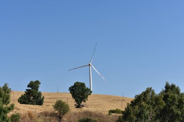 İtalya, Sicilya 'daki dağda rüzgar türbini. Rüzgar türbini ve kırsal İtalyan yaz manzarası. Mountain Eolic Parkı. Yenilenebilir enerji kavramı, yeşil ekolojik enerji üretimi. 