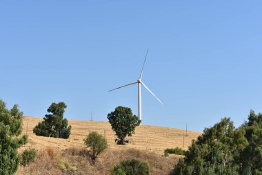 İtalya, Sicilya 'daki dağda rüzgar türbini. Rüzgar türbini ve kırsal İtalyan yaz manzarası. Mountain Eolic Parkı. Yenilenebilir enerji kavramı, yeşil ekolojik enerji üretimi. 