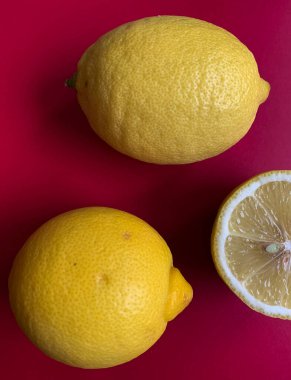 Canlı pembe bir arka planda taze limon deseni. Düz yatıyordu. Limonlar. C vitamini. Sanat eseri. Minimum yaz konsepti. Pembe arkaplanda tam ve yarıya indirilmiş limon ve metin için kopyalama alanı.