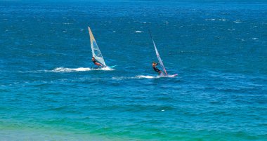 Rüzgârlı bir günde iki rüzgar sörfçüsü heyecanlı bir yolculuğun tadını çıkarır. Sporcular, yeteneklerini sergileyerek havada yakalanırlar. Canlı mavi okyanus dinamik ve enerjik bir zemin yaratır..