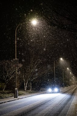 Huzurlu bir kış manzarası. Geceleri sessiz, aydınlık bir sokağa kar taneleri düşüyor.