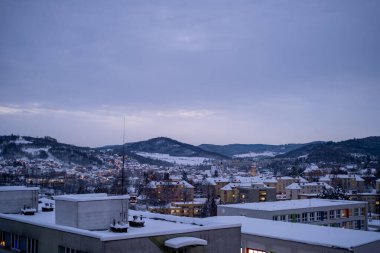 A tranquil winter townscape illuminated by twilight, with snow-covered rooftops and surrounding hills creating a serene evening atmosphere. Perfect for seasonal and landscape themes. clipart