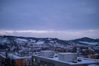 A tranquil winter townscape illuminated by twilight, with snow-covered rooftops and surrounding hills creating a serene evening atmosphere. Perfect for seasonal and landscape themes. clipart