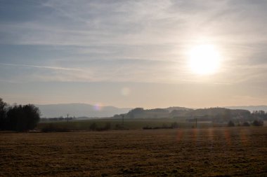Açık arazisi olan huzurlu kırsal alan ve güneş sabah sisi altında uzak tepelerin üzerinden yükseliyor..